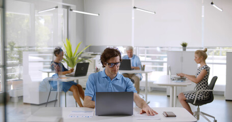 Multiethnic people in smart casual sitting at desk and working on computer in modern office