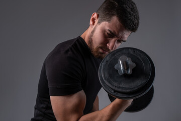 Concentrated young man doing bicep curls with dumbell