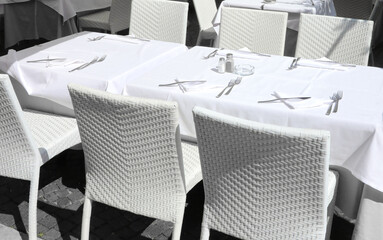 white tablecloths and white chairs in the restaurants waiting for the tourists