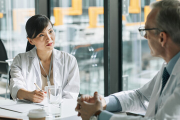 Portrait of female Asian doctor speaking to colleagues during medical meeting in conference room