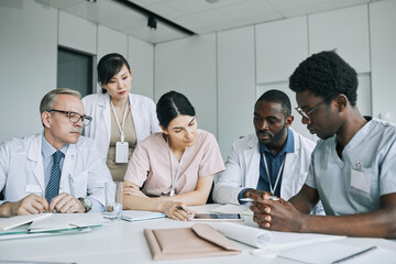 Large group of doctors working together at meeting table during medical conference
