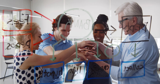 View through glass board of diverse team putting hands together celebrating success
