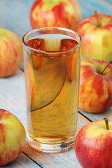 A glass with apple juice and ripe apples