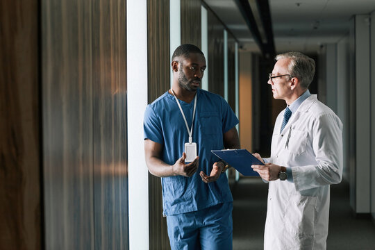 Waist up portrait of two doctors talking while standing in clinic hall, copy space