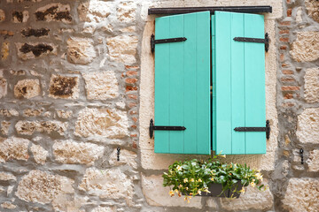turquoise old wooden window with shutters on facade of stone house