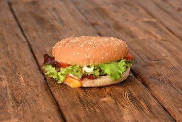 Juicy delicious hamburger with green salad on a wooden table.