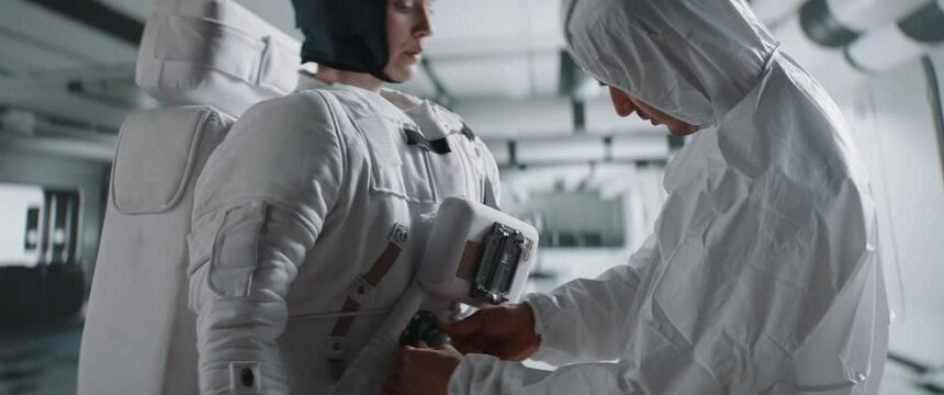 Crew member performing pre-flight inspection on a female astronaut space suit, rocket launch preparation check-up. Shot with 2x anamorphic lens