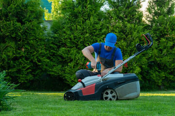 A professional repairman repairs a lawn mower, a man repairs a mower in his backyard