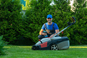 A professional repairman repairs a lawn mower, a man repairs a mower in his backyard