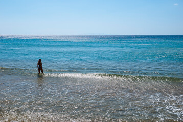 Andros Island, Greece - June 24, 2021: Woman enjoying the sea at a beautiful beach.