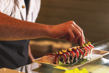 Professional sushi chef decorating sushi rolls
