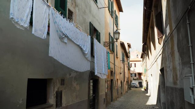 Beautiful narrow street in an ancient village Tuscania of Viterbo province, amazing medieval atmospheric mood with building exterior and hanging laundry outdoors. Italian culture, villages of heritage