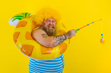Fat happy man with wig in head plays with the fishing rod