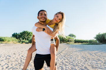 Smiling young couple having fun on the beach - candid portrait, travel and freedom concept