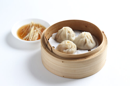 steamed Xiao long bao Shanghai small meat dumpling in bamboo basket with ginger vinegar sauce on white table chinese dim sum menu banquet restaurant halal food