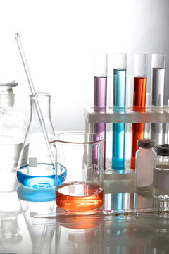 Vertical image of various of lab tubes,flasks and colorful liquids on the glass table