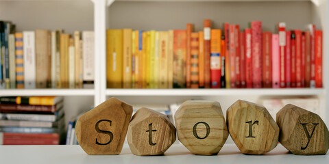 Word Story written on wooden irregular blocks in front of blurred bookshelf.