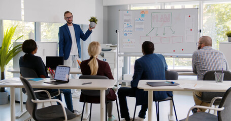 Business expert holding plant and explaining strategy chart to audience
