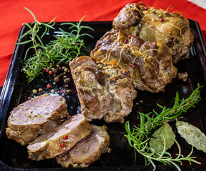 meat dish baked in the oven decorated with spices and rosemary on a dark background