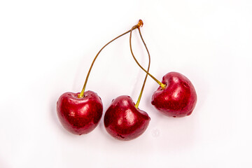 three ripe cherries on a light background