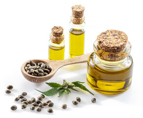Cannabis seeds in the wooden spoon and bottles of hemp oil isolated on white background. Close up.