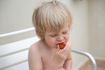 White child eats strawberries in summer close-up portrait
