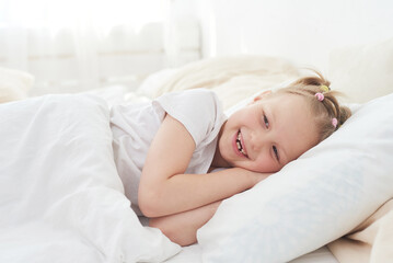 A little girl wakes up in the morning and smiles. Good dream
