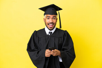 Young university graduate Colombian man isolated on yellow background surprised and sending a message