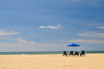 Beautiful beach on a sunny day with a row of beach lounger under a vibrant blue parasol