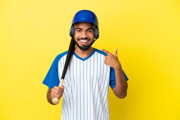 Young Colombian latin man playing baseball isolated on yellow background giving a thumbs up gesture