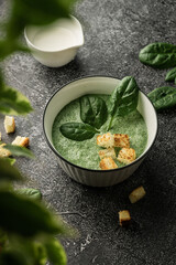 cream soup of green fresh spinach with cream and croutons for decoration. on a dark copyspace background, For menus and articles with recipes