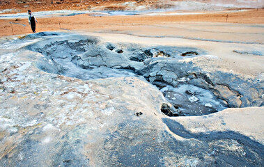 Young woman in overalls traveling in Hverir geothermal area in North of Iceland, Boiling volcano...