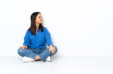 Young mixed race woman sitting on the floor isolated on white background . Portrait