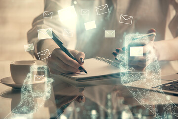 Double exposure of envelop icon hologram and woman holding and using a mobile device. E-mail concept.