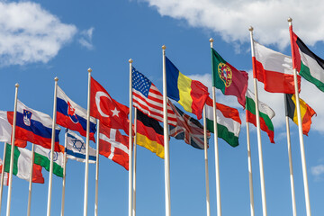 Obraz premium Flags of various states waving in the wind against the background of the cloudy sky. Flags of various countries together - as a symbol of global cooperation