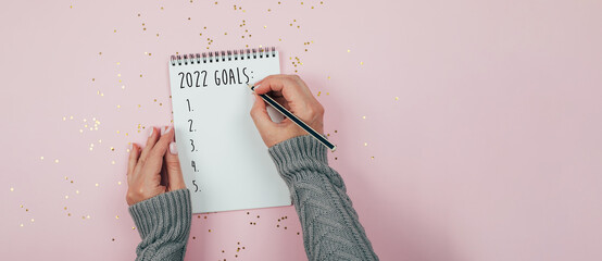New Year goals 2022. Woman's hand writing in notebook goals list. Concept of new year planning.