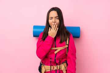 Young mountaineer girl with a big backpack over isolated pink background yawning