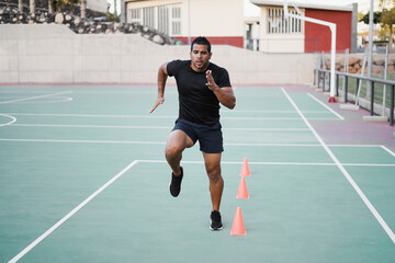Fototapeta premium Hispanic man doing speed and agility cone drills workout session outdoors - Focus on man face