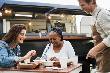 Fototapeta na wymiar Multiracial women eating at food truck restaurant outdoor - Summer and friendship concept - Focus on african american female face