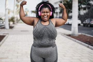 Happy curvy african woman doing workout routine outdoor at city park - Focus on face