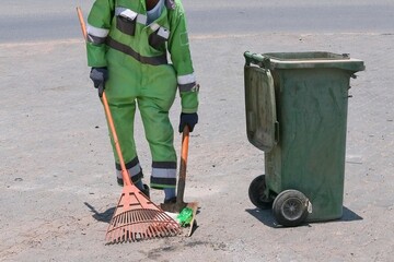 Street cleaning, male municipal worker in fluorescent uniform collecting street rubbish to...