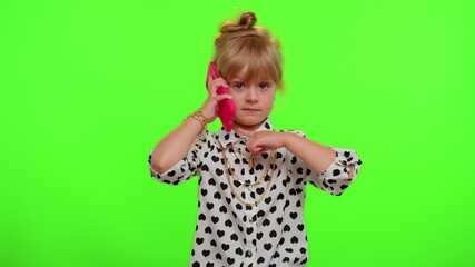 Hey you, call me back. Portrait of funny playful blonde child girl holding smartphone looking at camera doing phone gesture on chroma key, green screen wall background. Teen stylish kid children