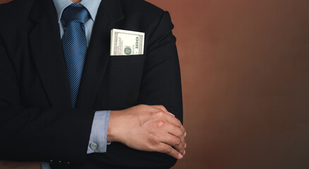 Businessman wearing a suit with US dollars in a suit pocket and arms crossed while standing in a studio with a vintage background with space for text. Business and finance concept