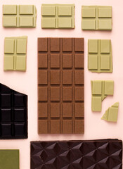 Different types of chocolate on a pink background. View from above
