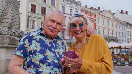 Elderly stylish tourists man woman looking for way using smartphone in old town Lviv, Ukraine....