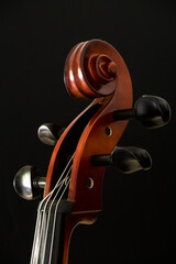 CLOSE UP OF CELLO SCROLL ON BLACK BACKGROUND.