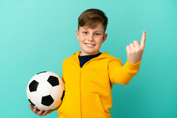 Redhead kid playing football isolated on blue background doing coming gesture