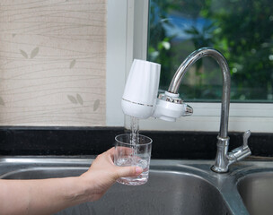 woman pouring water into glass from the water filter in the kitchen