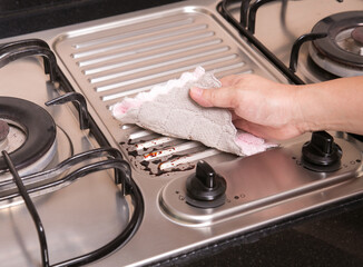 woman cleaning stained soy bean sauce on the stove with cloth