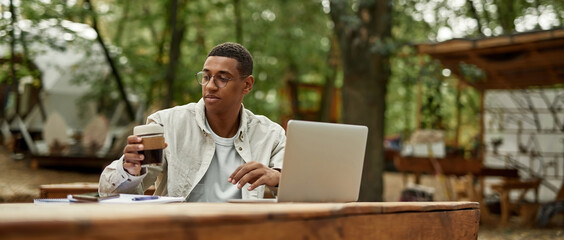 Cheerful young african american man working on laptop